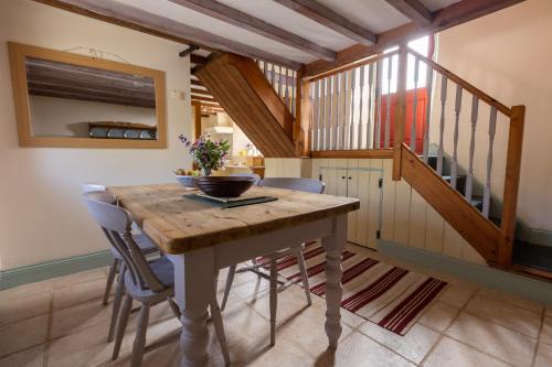 uma sala de jantar com uma mesa de madeira e uma escada em Delfryn Holiday Cottages em Solva