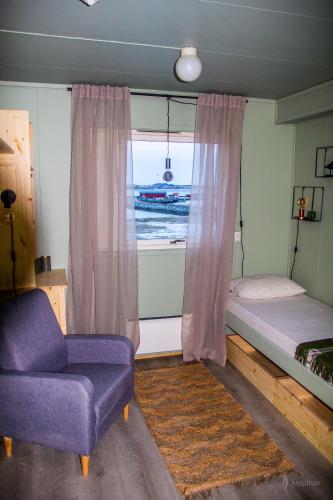 een slaapkamer met een bed, een raam en een stoel bij Kelp Lodge - Våg Smart City in Lekanger