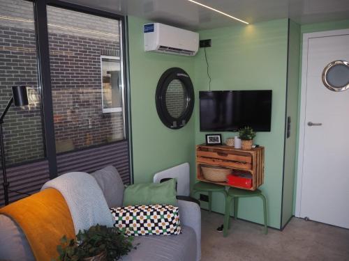 sala de estar con sofá y TV en Bed-on-a-Boat, en Giethoorn