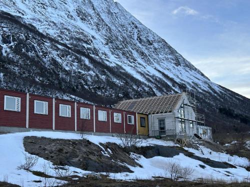 a building in front of a snow covered mountain at Kelp Lodge - Våg Smart City in Lekanger