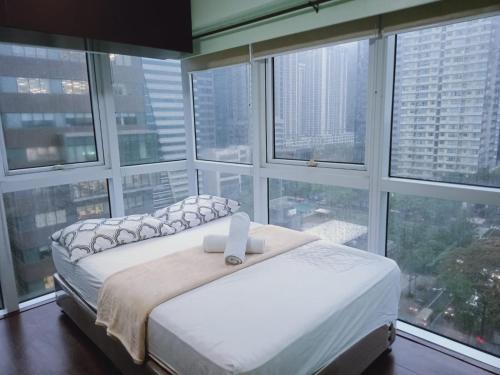 a bed in a room with large windows at 2 Bedrooms Units Forbes Area 5th Avenue BGC Center in Manila
