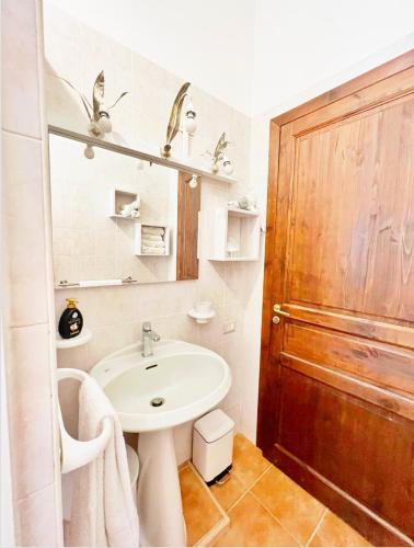 La salle de bains est pourvue d'un lavabo blanc et d'une porte en bois. dans l'établissement La Pavoncella Holiday House, à San Vito