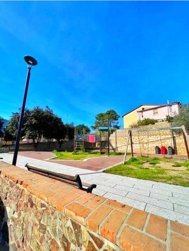 a bench on a brick wall with a light pole at La Pavoncella Holiday Home in San Vito