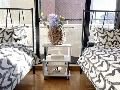 a bedroom with two beds and a table with a basket of flowers at S2 Shibuya House 850m from Shibuya Sta in Tokyo