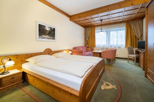 a bedroom with a large bed and a dining room at Ferienhotel Gasthof zur Post in Untertauern