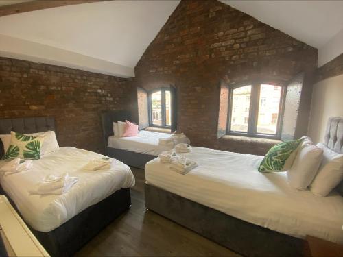a bedroom with two beds and two windows at Button Street by UStay Aparthotels in Liverpool