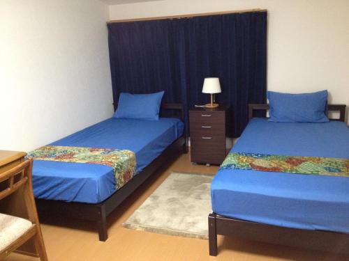 a bedroom with two beds and a table and a lamp at Rumah Kyoto Yu in Kyoto