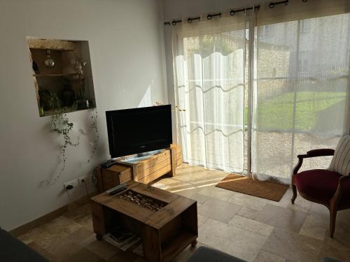 a living room with a flat screen tv and a table at Château La Fon du Berger in Saint-Sauveur