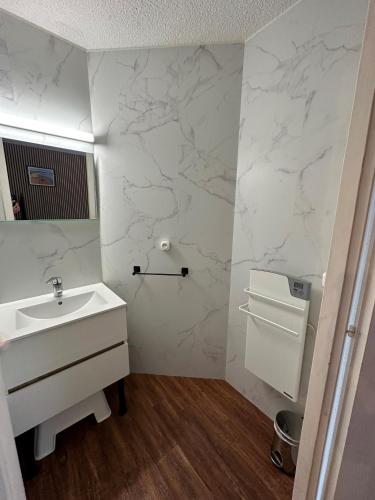 La salle de bains est pourvue d'un lavabo blanc et de murs en marbre. dans l'établissement Le Green des Halles Hossegor *T3*Parking*Clim, à Soorts-Hossegor
