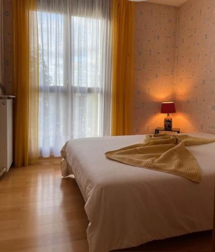 - une chambre dotée d'un lit blanc avec une lampe et une fenêtre dans l'établissement Nanterre Mont Valérien, à Nanterre