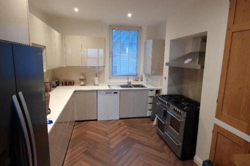 a kitchen with white cabinets and a sink and a stove at 4 bedroom house opposite the sea in Kent