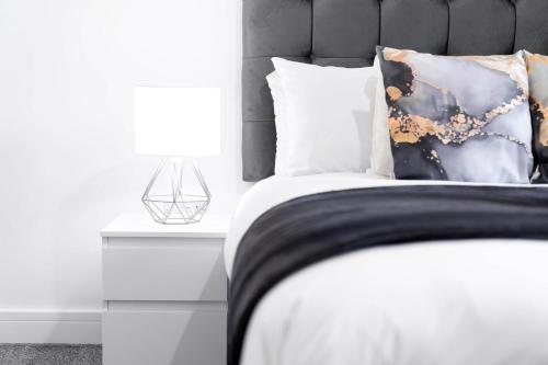 Schlafzimmer mit einem Bett mit einer schwarzen und weißen Bettdecke in der Unterkunft Smetwhick Deluxe 2 Bed Apartment - Balcony - Secure Parking - 4MC in Birmingham