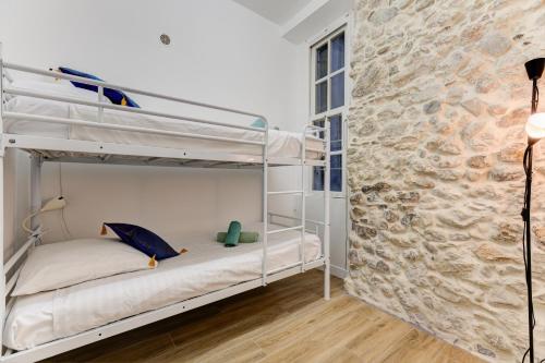- une chambre avec 2 lits superposés et un mur en pierre dans l'établissement Vieille Ville - 5 pers, AC, WIFI, à Nice