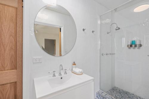 a white bathroom with a sink and a mirror at The Sandcastle - 4 Bedroom House in Woolgoolga