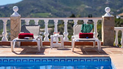 - deux chaises avec des oreillers rouges et verts à côté de la piscine dans l'établissement Casa Amparo Casitas Select, à Frigiliana