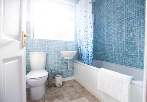 a blue tiled bathroom with a toilet and a sink at Honest Hospital House 1 in Southampton