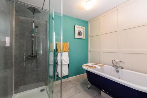 a bathroom with a tub and a glass shower at The Red Admiral Gosforth CA20 1BP in Seascale