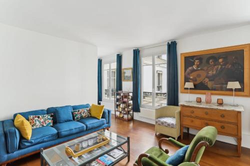 una sala de estar con un sofá azul y una pintura en Gros Caillou - Surcouf 2bdr, en París