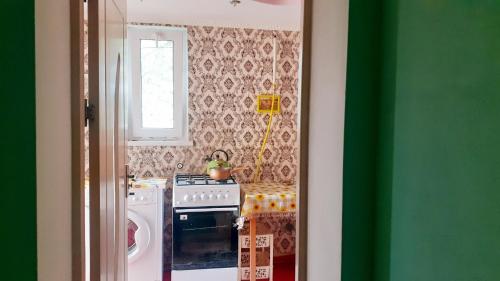 - une cuisine avec une cuisinière et un mur vert dans l'établissement SION In Ulmu, à Ulmu