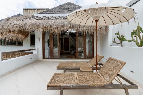 a patio with two chairs and an umbrella at Villa Alba, Berawa Beach in Canggu