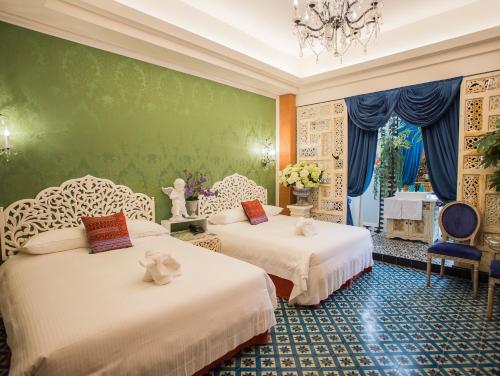 twee bedden in een kamer met een groene muur bij Anna King Hotel in Chiayi City