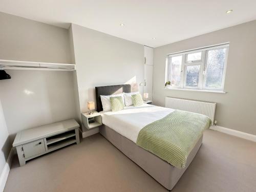 a white bedroom with a large bed and a window at 3-Bedroom Flat with FREE parking in the Heart of Hampton Hill Village in Hampton Hill