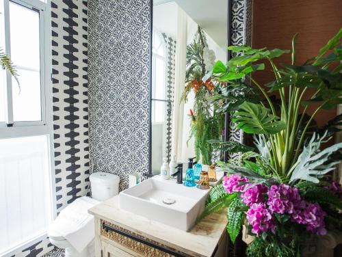 a bathroom with a sink and a mirror and flowers at Anna King Hotel in Chiayi City