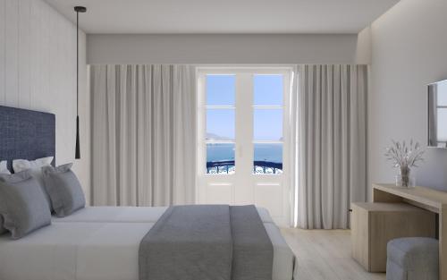 a bedroom with a bed and a large window at Nireus Hotel in Symi