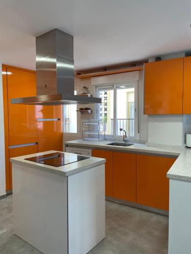 una cocina con armarios naranjas y blancos y fregadero en H&H Suite El Santisimo, en Granada