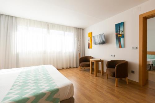 a bedroom with a bed and two chairs and a table at Daniya Alicante in Alicante