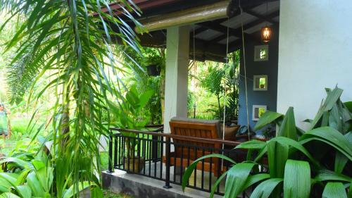 a porch with a bench and some plants at Leel’s Safari Cottage in Udawalawe