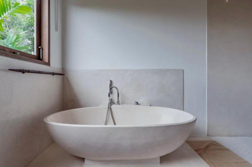 a white bath tub in a bathroom with a window at Villa Alba, Berawa Beach in Canggu