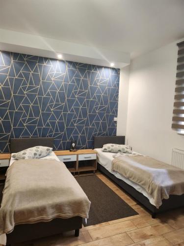a bedroom with two beds and a blue wall at Hacjenda in Radwanice