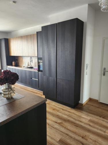 a kitchen with black cabinets and a wooden floor at Meridiem byt in Topoľčany