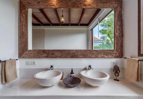 two sinks in a bathroom with a mirror at Villa Alba, Berawa Beach in Canggu