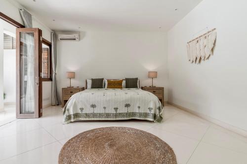 a white bedroom with a bed and a rug at Villa Alba, Berawa Beach in Canggu