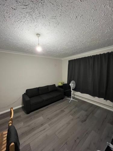 a living room with a black couch and a curtain at Briar Lodge in Woodford