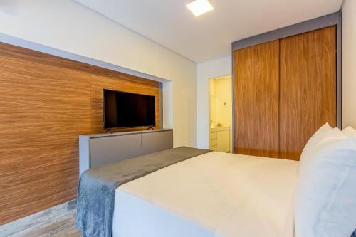 a bedroom with a large bed and a flat screen tv at Loft Duplex Metrô Vila Madalena NOVO E EQUIPADO in Sao Paulo