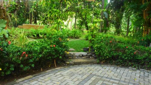 a garden with flowers and a brick walk way at Leel’s Safari Cottage in Udawalawe