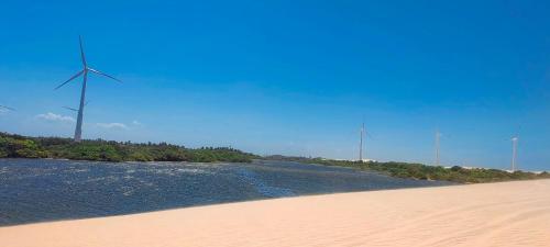 a river with windmills in the background on a beach at Villa Recanto do Mar - Icaraizinho de Amontada in Amontada