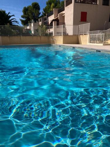 une grande piscine d'eau bleue devant un bâtiment dans l'établissement Beautiful house with shared pool and terrace, à Sanary-sur-Mer