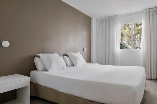 Un dormitorio con una gran cama blanca y una ventana en Prinsotel Alba & Spa, en Cala d´Or