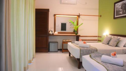 a hotel room with two beds and a mirror at Leel’s Safari Cottage in Udawalawe
