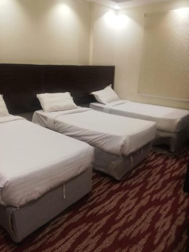 three beds in a hotel room with white sheets at مبني الششة 5 in Al Khansāk