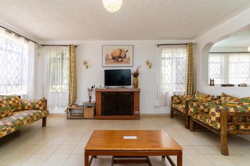 a living room with couches and a flat screen tv at Bonsai Villa in Nairobi