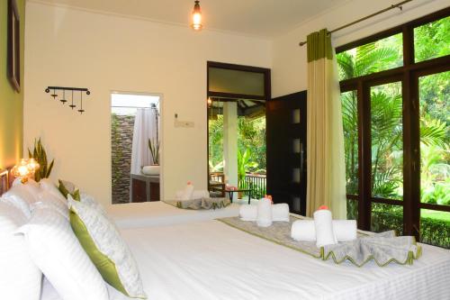 um quarto com uma cama grande e almofadas brancas em Leel’s Safari Cottage em Udawalawe