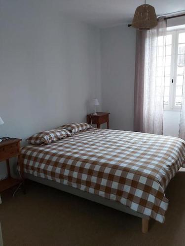 - un lit avec une couverture en damier dans une chambre dans l'établissement Gîte 5 pers en Périgord, à Siorac-en-Périgord