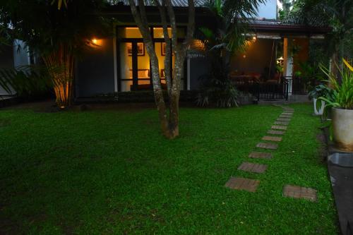 a lawn with a pathway in front of a house at Leel’s Safari Cottage in Udawalawe
