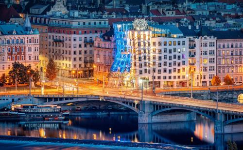 eine Brücke über einen Fluss in einer Stadt nachts in der Unterkunft Dancing House - Tančící dům hotel in Prag
