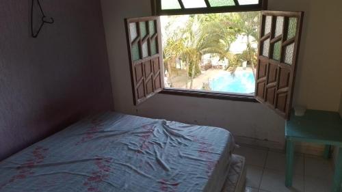 um quarto com uma cama e uma janela com uma piscina em Casa 3/4 Guarajuba BA em Camaçari